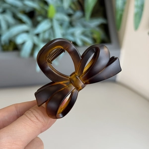 Detail of tortoise shell resin hair claw clip with minimalist bow design in dark brown