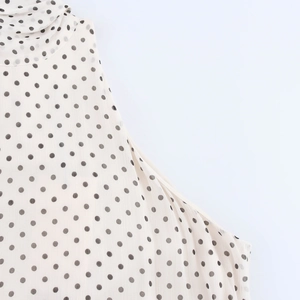 Detailed view of polka dot halter neckline and sleeveless chiffon fabric on maxi dress