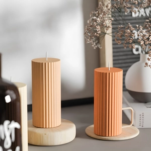 Modern pillar candles with vertical ribbed textures on a decorative wooden tray