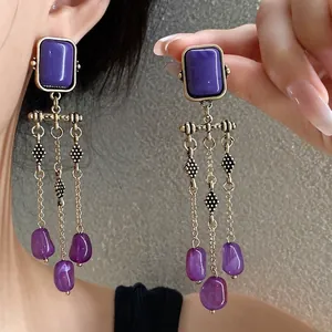 Detailed view of vintage gold earrings featuring purple gemstones and long elegant tassels