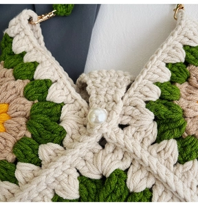 Close-up of handmade crochet sunflower bag with pearl buckle and green knit texture
