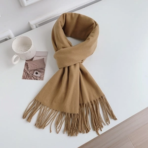 Detailed view of soft camel faux cashmere scarf with fringe on a minimalist desk setup