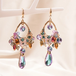 Detail of gold earrings with crystal butterfly, flowers and teardrop pendants