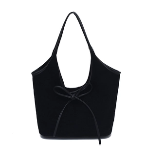 Close-up of black suede shoulder bag with elegant bow detail and minimalist U-shaped top
