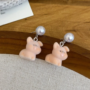 Close-up of cute pink flocked pig earrings with white pearl studs and silver pins