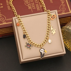 Golden Halloween necklace with pumpkin and ghost charms on a beige jewelry box