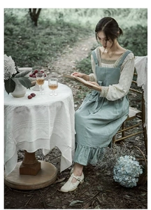 Close-up of light blue cotton ruffled apron featuring vintage pastoral style on model