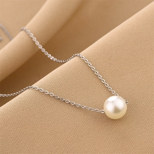 Minimalist pearl necklace with silver chain on textured fabric background