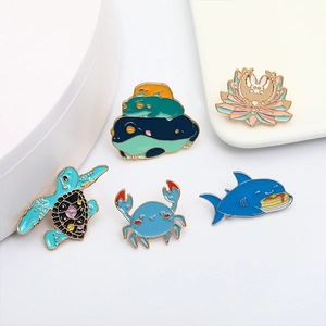 Set of five creative animal enamel pins including crab and shark on a clean white background