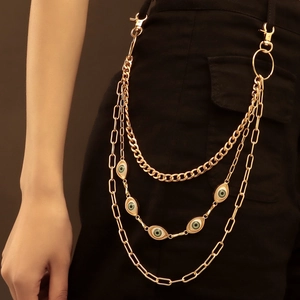 Detail of layered gold hip chain featuring green eye pendants and lobster clasp hooks