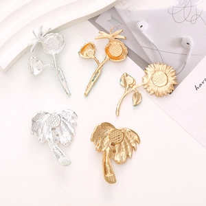Golden and silver sunflower and palm tree metal hair accessories on a white tray