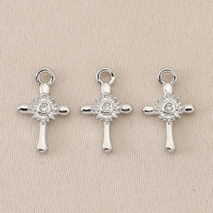 Macro shot of silver baroque cross pendants with central zircon stone and radial texture