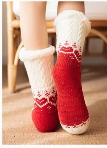 Detail of red knit socks with white faux fur cuffs and anti-slip grips on the bottom