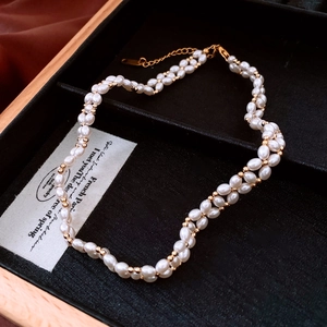 Gros plan d'un collier de perles à double rangée avec perles dorées 18 carats et boîte