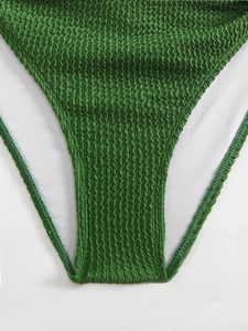 Detailed close-up of dark green textured ripple fabric on bikini bottom with white mesh lining