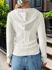 Rear view of white cable knit hooded sweater with ribbed hem on a model outdoors
