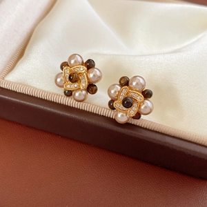 Gros plan de boucles d'oreilles fleurs dorées avec perles et zircons dans un coffret