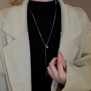 Silver Y-shaped tassel necklace with square slider and beads on a wool coat
