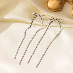 Silver bow knot long tassel drop earrings on beige silk fabric background