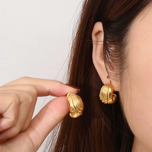 Close-up of golden ribbed croissant earrings worn on ear showing vintage metallic texture