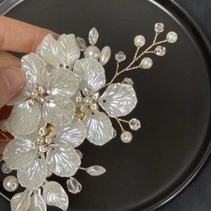Detail of bridal hair clip with white shell flowers, pearls and crystals on gold wire