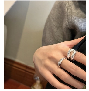 Primer plano de anillos de plata de ley S925 con detalles texturizados en la mano de una modelo