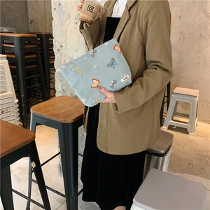 Close-up of light blue canvas makeup bag with colorful butterfly embroidery detail