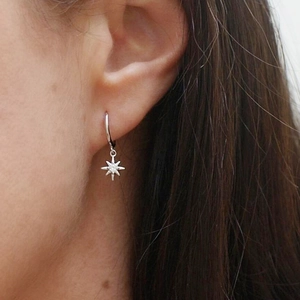Close-up of S925 sterling silver star-shaped hoop earrings worn by a model