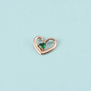 Détail du pendentif cœur en or rose avec une petite pierre de naissance verte facettée