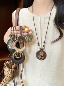 Close-up of Bohemian wood bead necklace with intricate bronze hollow leaf and circle pendant
