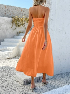 Close-up of the flowing orange fabric and halter neckline on a long summer vacation dress