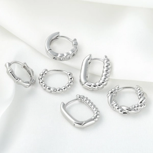 Set of 6 minimalist silver geometric hoop earrings on white silk fabric background