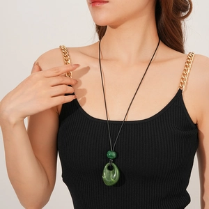 Close-up of wax cord necklace with green beads and large droplet pendant on model