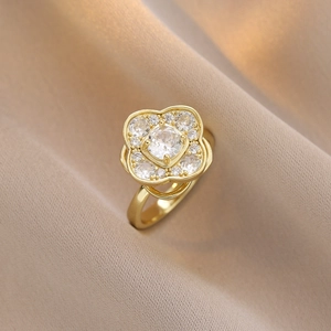 Primo piano di un anello a quadrifoglio dorato con cristalli su tessuto beige