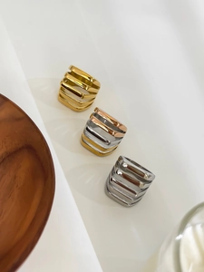 Close-up of three geometric hollowed stainless steel rings in gold and silver finish