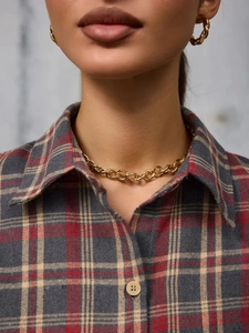 Golden chunky chain necklace and twisted textured earrings set on a plaid shirt