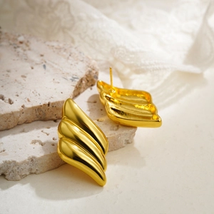 Close-up of triple-layered 18K gold-plated wing earrings on natural stone background