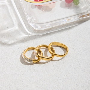 Three-piece gold ring set featuring pavé diamonds, a center zircon, and wavy band