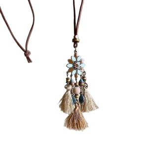 Collier ethnique bohème avec motif floral en émail et pompons doux en coton beige