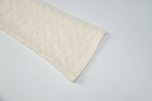 Detailed macro view of off-white knit fabric with 3D polka dot texture and soft mesh mesh