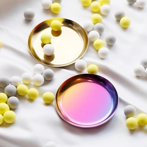 Top view of gold and iridescent stainless steel round trays on white silk background