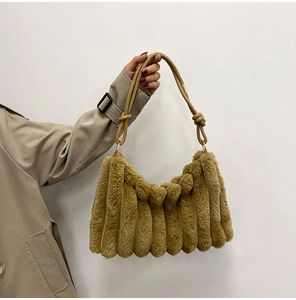 Brown faux fur handbag with wavy texture and PU leather strap held by a model