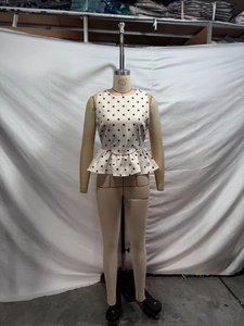 Detail of white sleeveless polka dot waist-slimming top with elegant flared hemline