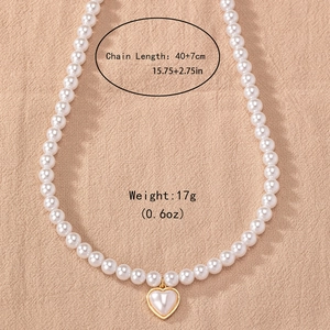 Elegant pearl necklace with gold-edged heart pendant on a textured beige background