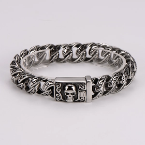 Macro view of men's vintage steel bracelet featuring etched totems and skull clasp detail