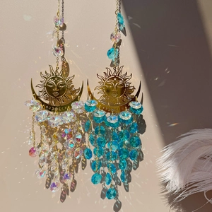 Close-up of metal sun and moon wind chimes with colorful crystals reflecting rainbow light