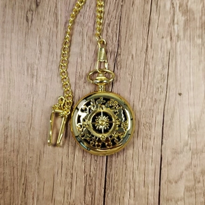 Golden pocket watch compass with hollow mechanical gear design on light wood background