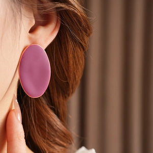 Dettaglio di grandi orecchini ovali magenta smaltati con perno in argento