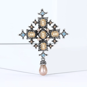 Detailed view of vintage silver baroque cross brooch with crystals and teardrop pearl