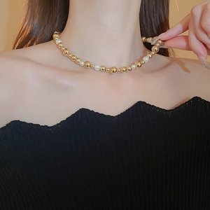 Detailed view of elegant gold metal and white pearl choker necklace on a female model